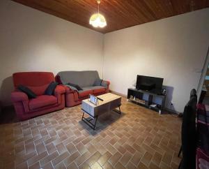 a living room with two red couches and a tv at Maison proche du lac in Priziac