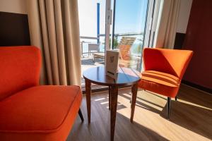 a room with two chairs and a table and a window at LOGIS HOTEL - La Petite Rade in Le Havre