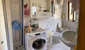 a bathroom with a washing machine and a toilet at Blu Mare di Irma in Roseto Capo Spulico