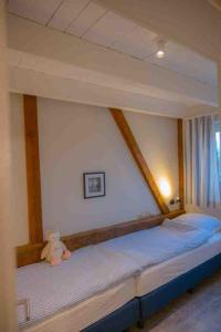 un orsacchiotto seduto su un letto in una camera da letto di Ferienwohnung Himmelsbesen - Inselhof Fehmarn a Fehmarn