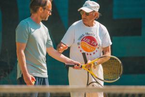 Due uomini stanno parlando su un campo da tennis. di Ferienwohnung Himmelsbesen - Inselhof Fehmarn a Fehmarn