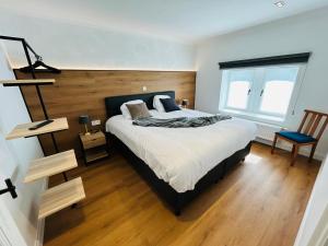 Un dormitorio con una cama grande y una silla. en Maison Jacqueline, en Nieuwpoort