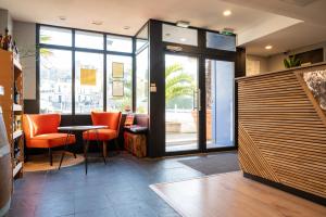 a restaurant with orange chairs and a table and glass doors at LOGIS HOTEL - La Petite Rade in Le Havre