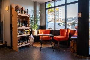 a bar with two orange chairs and a table and bottles at LOGIS HOTEL - La Petite Rade in Le Havre