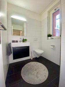 a white bathroom with a sink and a toilet at City Views Apartment am Schaffhauserplatz in Zürich