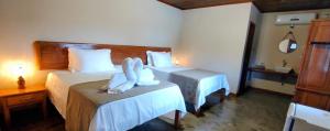 a hotel room with two beds with towels on them at Pousada Vila Madeira in Sítio Selva de Pedra