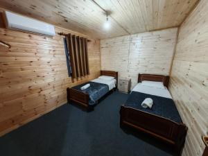 two beds in a room with wooden walls at Riverside Komani Lake in Koman