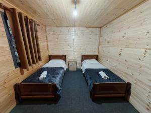 two beds in a room with wooden walls at Riverside Komani Lake in Koman