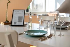 a table with a plate and glasses and a laptop at BRIGHT by Interior Apartments in Kassel