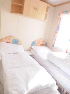 two twin beds in a room with a window at Beachside, Family-friendly, WiFi, 6 berth caravans in Ingoldmells