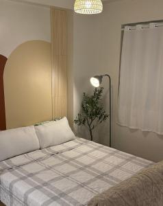 un letto in una camera con lampada e pianta di Meraki Stays - ETANA - SMDC Hope Residences a Trece Martires