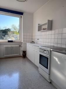 a white kitchen with a stove and a window at Monteurwohnung Osnabrück 3-Zimmer mit Balkon in Osnabrück