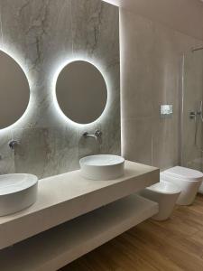 a bathroom with two sinks and a toilet and two mirrors at La dimora degli scrittori in Porto Empedocle