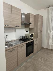 a kitchen with wooden cabinets and a sink and a microwave at Altro Cielo in La Maddalena +12 photos