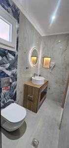 a bathroom with a sink and a toilet and a mirror at Sidari Escapes By The Beach in Sidari