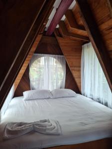 a bed in a attic with a window at Cabaña Alamo frente al mar in Capurganá