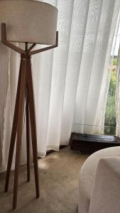 une table devant une fenêtre avec un rideau blanc dans l'établissement Bangalô de Pedras, à São Thomé das Letras