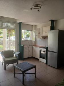 a kitchen with a refrigerator and a chair and a table at Spacieux appartement avec terrasse et piscine au Diamant in Le Diamant