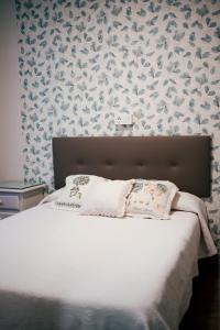 1 dormitorio con cama blanca y papel pintado con motivos florales en Casa Milladoiro, en Miño