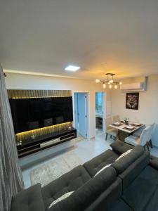 a living room with a couch and a large television at Loft SUNSET - 8 ANDAR in Dourados