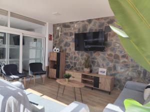 a living room with a tv on a stone wall at Alojamiento Lo Trabucador in El Poblenou del Delta