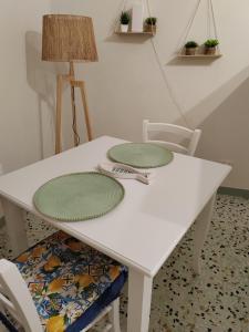 a white table with two green plates on it at La casa di Maria in Lipari