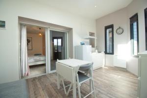a white kitchen with a table and a refrigerator at Le Petit Moulin I Plage et terrasse in Crozon +7 photos