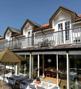 a house with a balcony with tables and chairs at Nevlunghavn Gjestgiveri in Nevlunghavn