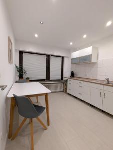 a white kitchen with a wooden table and a chair at Wohlfühl Apartment ruhig wohnen, alles vor Ort nähe der Niederlande in Gangelt +5 photos