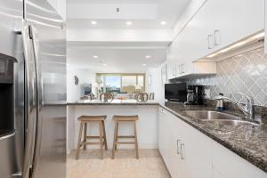 a kitchen with white cabinets and a stainless steel refrigerator at Charming 2 BR Longboat Key condo with ocean view in Longboat Key