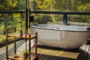 a bath tub in a bathroom with a large window at Cabana Mantiká in Sapucaí-Mirim +45 photos