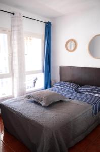 a bed in a bedroom with a blue curtain at los cristianos pool & sun apartment in Los Cristianos +31 photos
