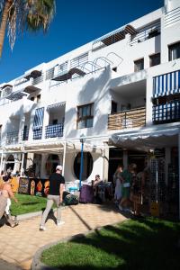 a group of people walking in front of a building at los cristianos pool & sun apartment in Los Cristianos