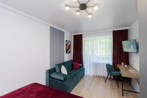 a living room with a green couch and a desk at CityApartments Kyiv Vokzalna in Kyiv