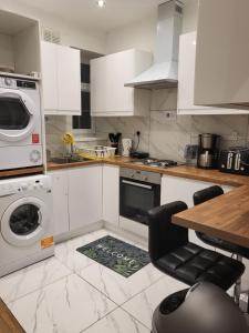 a kitchen with white cabinets and a washer and dryer at Marvellous property for 8 people in Battersea - Zone 1, 3 min walking from the main Station in London