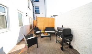 a patio with chairs and a grill on a building at Open Mind Property - HotTub, 2 Guests & 1 Bed in Bognor Regis