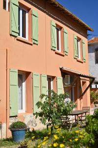 un edificio con ventanas con contraventanas verdes y mesa de picnic en Légèreté aux Mûriers, en Le Lavandou