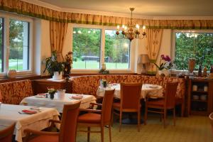 a dining room with tables and chairs and windows at Pension Schlömmer in Sankt Gilgen