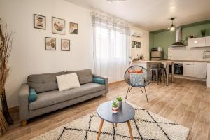 a living room with a couch and a table at Cosy Green Clim Wifi Centre ville 2 pers in Lézignan-Corbières +12 photos
