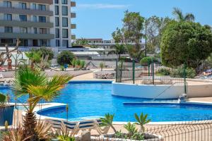 a swimming pool with chairs and a building in the background at Perla Paraisó in Playa Paraiso