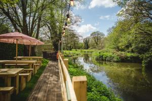 einem Kanal mit Tischen und einem Regenschirm neben einem Fluss in der Unterkunft The Stag on the River in Godalming