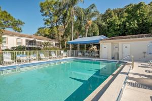 una piscina con sillas, un edificio y árboles en Charming 2 BR condo in The Meadows community, en Sarasota