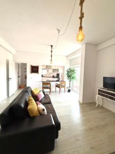 a living room with a black couch and a kitchen at Espectacular apartamento na praia a 20 min de Lisboa in Costa da Caparica +16 photos