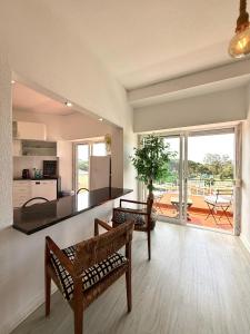 a living room with two benches and a kitchen at Espectacular apartamento na praia a 20 min de Lisboa in Costa da Caparica