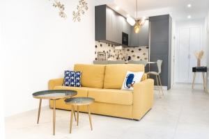 a living room with a yellow couch and two tables at Torre Solana 41 in Cádiz