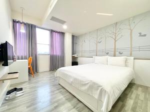 a bedroom with a white bed and trees on the wall at 沐眠宿 Moment Inn - 快速入住 好停車 in Tainan
