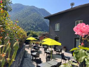 a patio with tables and chairs and yellow umbrellas at B&B Cà Nosa in Gordevio