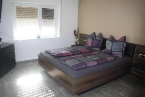 a bedroom with a bed with purple pillows and a window at Ferienwohnung Hengl in Ettenheim