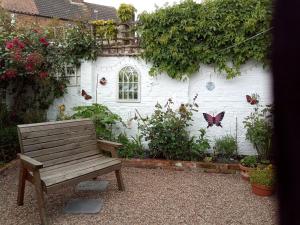 a wooden bench sitting in front of a building with butterflies at Pankhurst, Louth in Louth