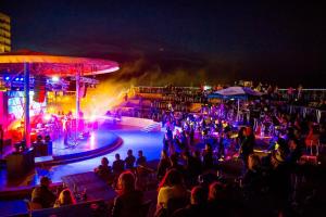 Une foule de gens assis autour d'une piscine la nuit dans l'établissement Studio Ivana by Blaxy Residence, à 23 August 14 autres photos